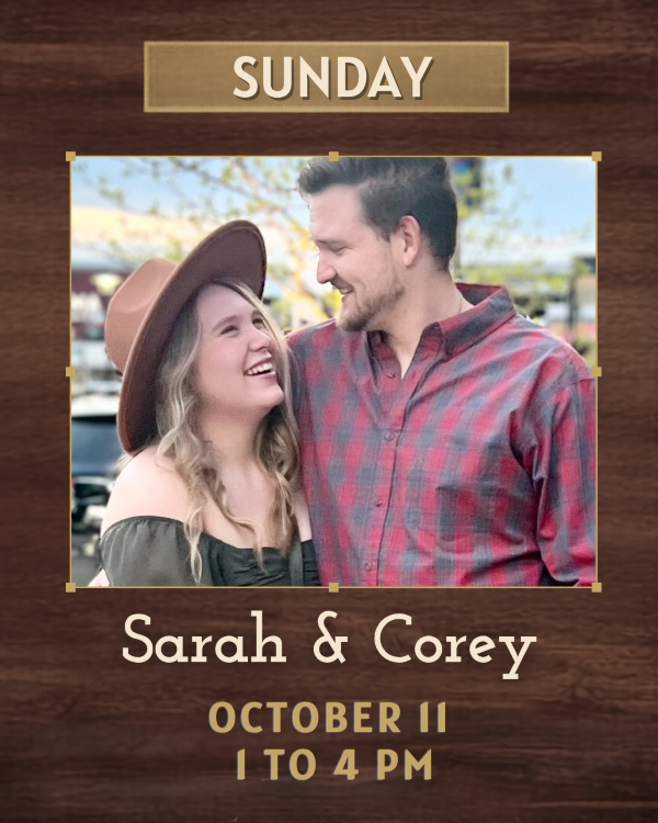 A woman in a wide brimmed hat holding on to a man, they are smiling at each other